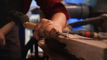 Craftsperson carving into wood using chisel and hammer in carpentry shop with precision. Manufacturer in studio shaping wooden pieces with tools, making wood art, camera B close up shot photo