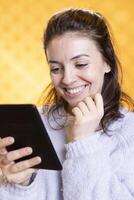 Woman amused by humorous ebook, conveying joy of reading concept, studio background. Geek enjoying comical digital novel on ereader screen, giggling at jokes, showing appreciation for literature photo