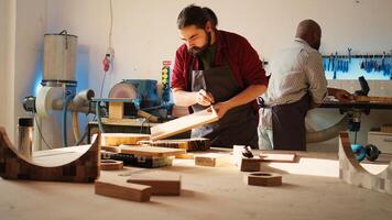 Carpenter in assembly shop starting renovation project on timber block, applying lacquer on surface. Woodworking specialist coloring wood plank with paintbrush, enjoying diy hobby, camera B photo