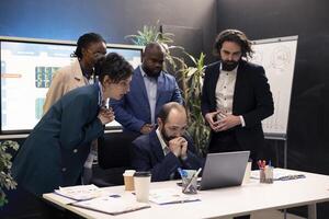 Business workers analyzing project updates and details to ensure goal achievement, evaluating statistics data on laptop and finding ways to obtain new capital. Enterprise management team. photo