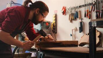 Man carving intricate designs into wood using chisel and hammer in carpentry shop, enjoying diy hobby. Woodworking specialist in studio shaping wooden pieces with tools, making wood art, camera B photo