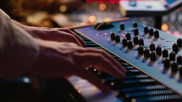Young singer playing piano electronic keyboard in control room, recording new music with midi controller and mixing console. Talented composer practicing on synthesizer in studio. Camera A. photo