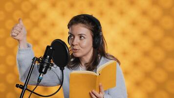 Voice actor looking to producer off camera to know when to start narrating book, producing audiobook. Narrator doing counting on fingers gesturing before starting digital recording of novel, camera A photo