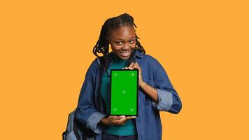 Smiling african american woman presenting tablet with green screen display, isolated over studio background. Cheerful BIPOC person creating promotion with chroma key device, camera A photo
