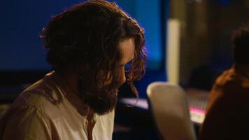 Singer performer creating a song on piano midi controller in studio, recording notes on electronic keyboard. Artist musician composing and producing tracks with technician. Camera A. photo