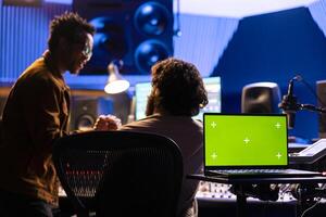 Musician and sound designer working on a new hit with isolated display, editing and adjusting volume levels on tracks recorded. Team of artists producing music and composing tunes in control room. photo
