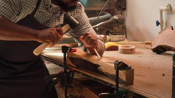 African american manufacturer shaping raw timber using chisel and hammer, creating wood art, making precise cuts. Artist making handmade wood sculptures, engraving lumber with tools, camera A close up photo