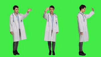 Friendly physician inviting people to come closer to her against greenscreen backdrop, calling patients over and smiling. General practitioner asking persons to approach her. Camera A. photo