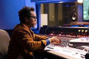 Music producer operating audio console in control room with professional editing and mixing equipment, post production concept. Sound designer processing tracks, digital software. photo