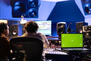 Artist and technician processing new sounds in professional studio and using audio console to edit tracks. Team of musicians producing a new album and creating music, pressing buttons and switchers. photo