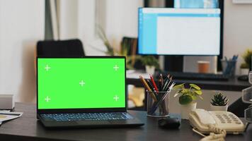 Office with green screen laptop and display in background with clients appointment list, panning shot. Chroma key notebook in financial department and customers schedules list in the back on monitor photo