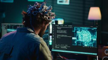 Computer scientist puts EEG headset on, starting mind upload process, trying to gain bionic powers. Man using high tech neuroscientific gear to transfer consciousness into cyberspace, camera A photo