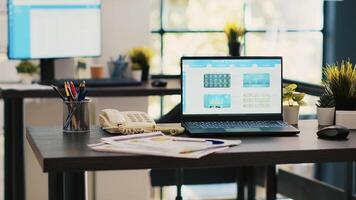 Stock market diagrams with charts and stock figures on laptop sitting on desk in empty workplace. Forex investment listings displayed on notebook screen in financial department, panning shot photo
