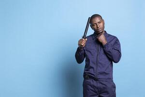 Security officer poses with a police baton and his fist clenched, making threats in case of attack or emergency fights. Guard on protection duty trained to punch and use his uniform weapon. photo