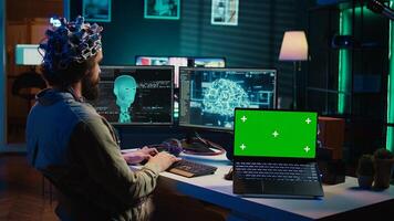 Computer scientist uploading brain into cyberspace, gaining digital persona using green screen laptop. Neuroscientist merging mind with AI, uploading consciousness into chroma key device, camera B photo