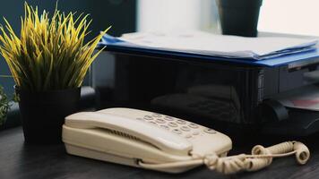 Company paperwork on top of printer, telephone and mini house plants on office desk close up. Business documents, printing machine and phone on table in accounting workplace photo