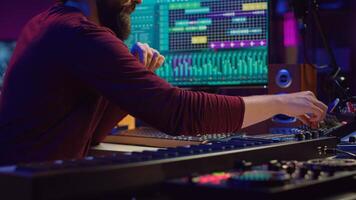 Music composer producing soundtracks using stereo panel controls and soundboard, twisting pre amp knobs for mixing and mastering tunes. Sound engineer adjusting volume in home studio. Camera A. photo
