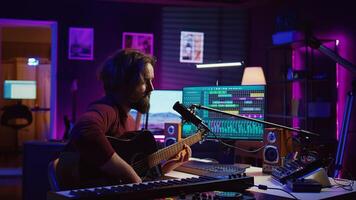 Artist with condenser microphone composing a song on guitar, working on mixing and mastering music. Producer recording tunes and adding sound effects in post production. Camera B. photo