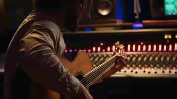 Songwriter composing a song with sound engineer in professional studio, recording session with his electro acoustic guitar in control room. Musician producing tracks with mixing console. Camera A. photo