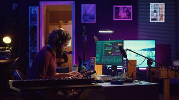 Joyful artist playing piano keyboard and recording tunes for mixing and mastering session, enjoying midi controller performance in home studio. Energetic music producer creating soundtracks. Camera A. photo
