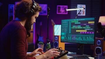 Music producer recording piano keyboard notes and editing them on a mixing console in his home studio. Skilled artist implementing advanced sound mixing techniques, equalization tools. Camera B. photo