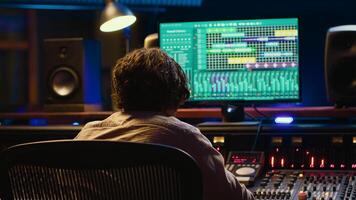 Audio expert does mixing and mastering on tracks using digital editing software in studio, producing new music. Skilled sound designer adjusting volume levels by using switchers and faders. Camera A. photo