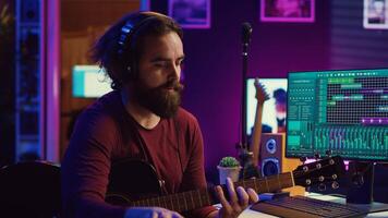 Musical composer recording his guitar tunes and adding piano key sounds, creating a beautiful song with mixing console and daw software. Sound engineer working with electronic tools. Camera B. photo