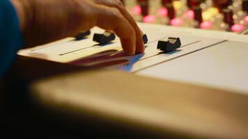 Audio expert recording and editing tracks with mixing console, twisting mixer knobs and changing settings. Sound engineer working in control room to produce music, key buttons. Close up. Camera A. photo
