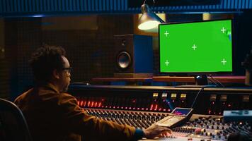 African american sound engineer working in control room with mixing console, tracking music and editing by adjusting volume levels. Skilled technician adjusting volume levels with buttons. Camera A. photo