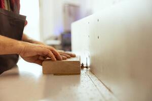 Man using edge jointer in assembly studio, performing specialized cuts, making wooden objects, close up shot. Focus on spindle moulder used by cabinetmaker for smoothing out panels photo