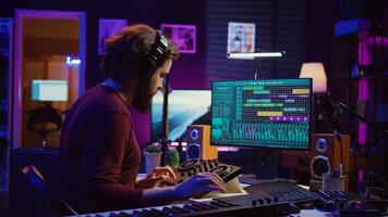 Audio engineer working with soundboard to create the perfect sounds for his new songs, recording and mixing audio. Music producer adjusts volume levels during recording sessions. Camera B. photo
