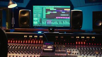 Empty soundproof control room in professional recording studio, stereo equipment with sliders and faders on panel board. Professional post production space with audio recording software. photo