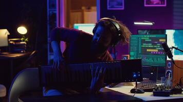 Energetic confident artist playing electronic piano in home studio, recording midi controller synthesizer notes to add audio effects. Cheerful sound engineer having fun with keyboard. Camera A. photo