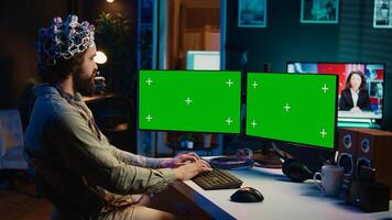 Engineer with EEG headset on programming brain transfer into computer virtual world on isolated screen monitors. Transhumanist using neuroscience to gain digital soul through chroma key PC, camera B photo
