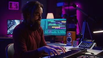 Audio engineer doing recording session with piano keyboard in home studio, mixing and mastering sounds to create new music. Musician playing midi controller synthesizer, producing tunes. Camera B. photo