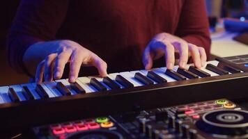 Music producer playing his song on piano keyboard and singing at microphone, recording soundtrack to edit on mixing console. Composer working with synthesizer in home studio. Camera A. photo