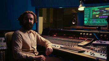 Sound engineer mixing and mastering tracks in professional recording studio, working with daw software and pushing sliders to adjust volume levels and edit audio recordings. Control room. Camera B. photo