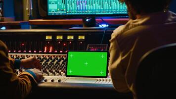 Artist and sound designer examine digital editing software and mockup on tablet, collaborating on composing a hit for new album. Musician working with audio technician in studio. Camera A. photo