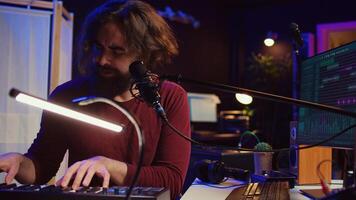 Skilled musician composing a song on piano midi controller, working with mixing console and daw software to record music. Artist singing at microphone, mastering his acoustical notes. Camera B. photo
