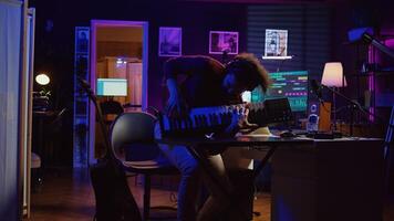 Energetic confident artist playing electronic piano in home studio, recording midi controller synthesizer notes to add audio effects. Cheerful sound engineer having fun with keyboard. Camera B. photo