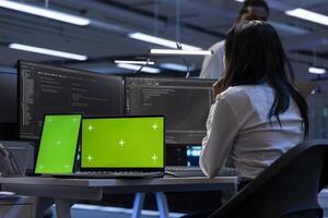 Technician in data center using isolated screen tablet and laptop to check for server issues arising due to high CPU usage. Server hub worker fixing insufficient memory errors with chroma key devices photo