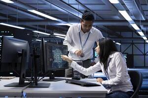 Team of technicians doing maintenance on server hub to optimize it for data processing requirements of artificial intelligence workloads. Teamworking employees inspecting neural network data center photo