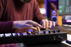 Audio engineer works with recording gear in his home studio, learning to use mixing console and pre amp knobs to add sound effects on soundtracks. Artist editing new tunes, production techniques. photo