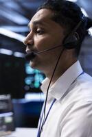 Data center agent supporting engineering team doing hardware maintenance, talking in headset microphone. Worker in high tech server room facility coordinating technicians using mic photo