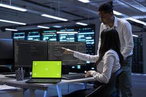 Team of technicians using mockup laptop to check server clusters configuration settings. Teamworking experts checking event logs in monitoring software to find faulty data center hardware root cause photo