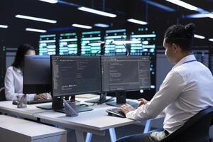 Technicians in data center workspace running system diagnostic tests and error checking utilities to fix problems. Employees looking for network issues affecting rigs performance and connectivity photo