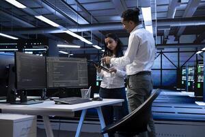 Tablet used by team of programmers in server room to find network issues affecting supercomputer performance. IT staff members fixing slow data transfer rates in data center photo