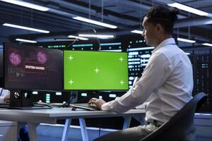 Engineer in server hub using green screen PC to stop hacker passing company firewall and stealing sensitive user data. Worker looking at mockup computer display, seeing security breach notification photo