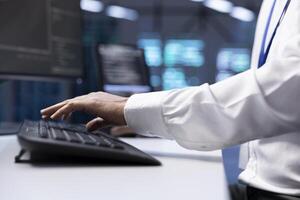 Software developer in data center checking equipment performance on computer after upgrading hardware. Close up shot of IT worker doing maintenance on storage devices in servers farm photo