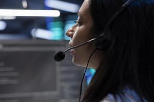 Data center operator assisting project teams with complex installations, issuing commands though headset mic. Expert in server hub communicating with engineers in remote call, close up photo
